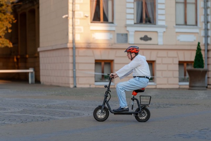 Мужчина в шлеме едет по улице на электросамокате